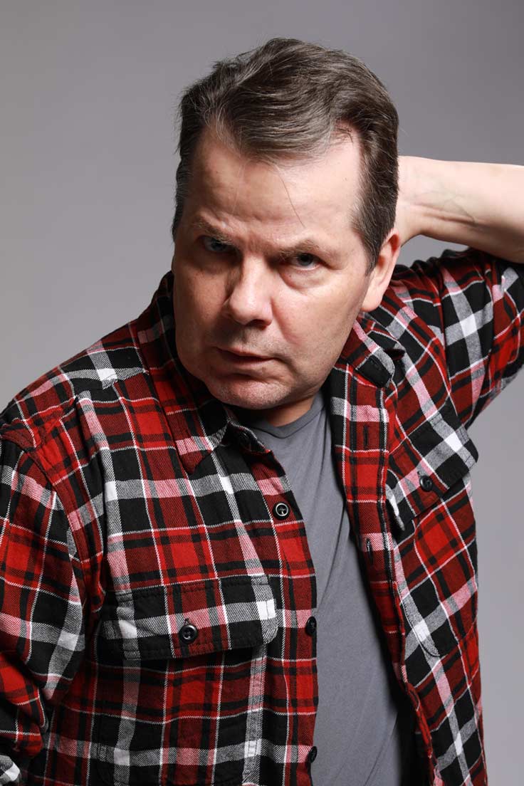 Photo of Bruce McCulloch with his hand on the back of his head like he has just swept his hair back.