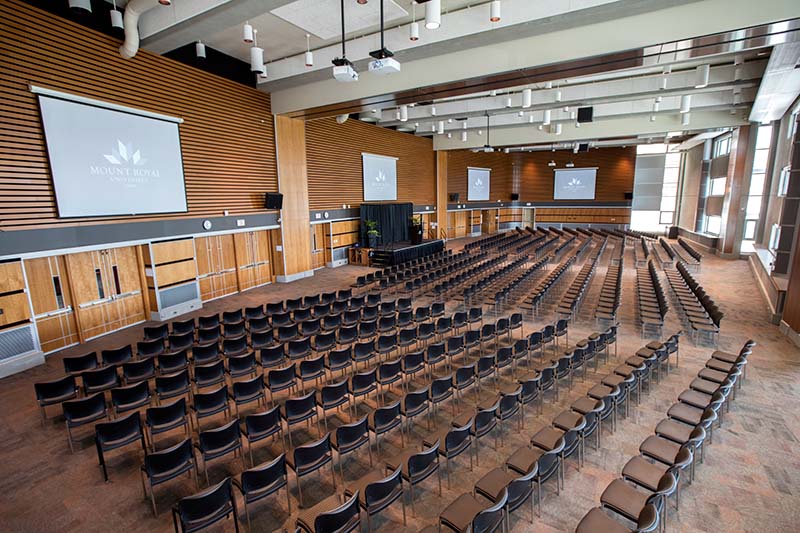 Photo of a large conference room filled with chairs and a stage.