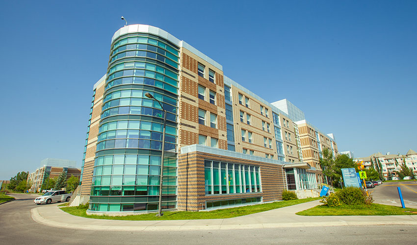 A photo of West Residence - a curved blue building with dark and light bricks creating a pattern.