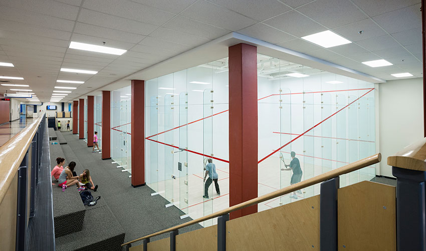 A row of squash courts and rows of benches to view the courts.