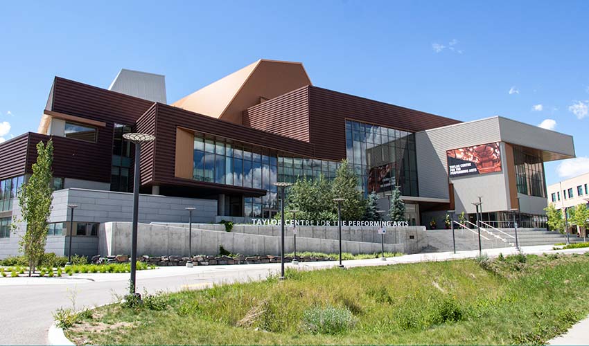 The front entrance to an angular building made of lots of copper sheeting and cement