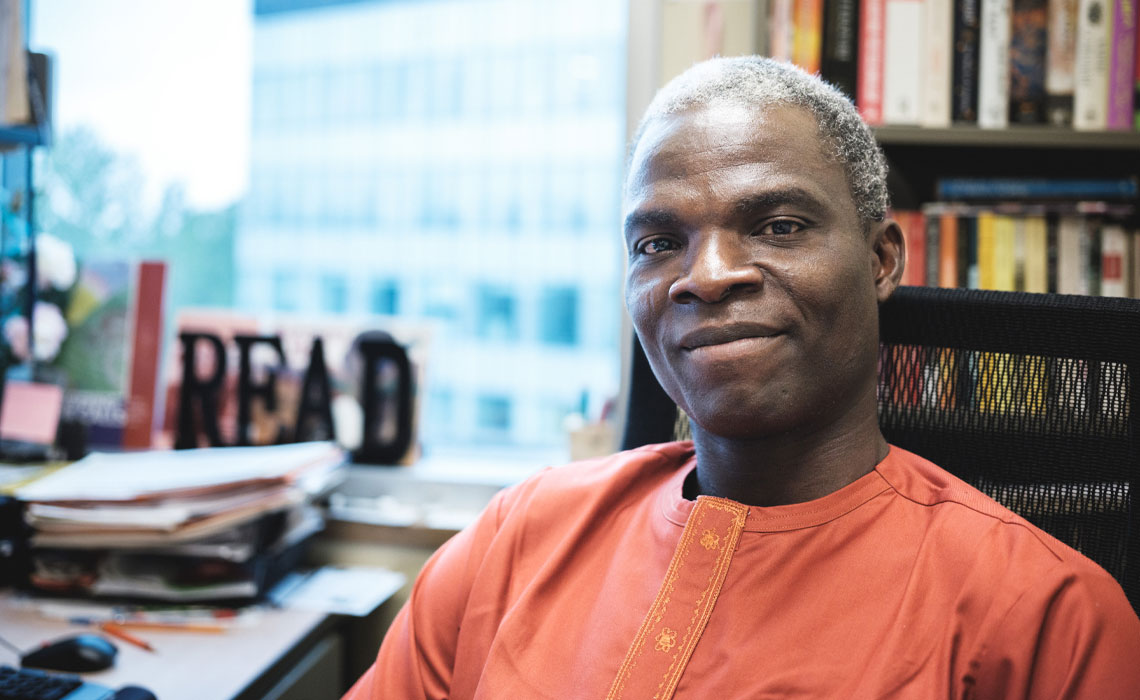 Ademola Adesola seated at his desk.