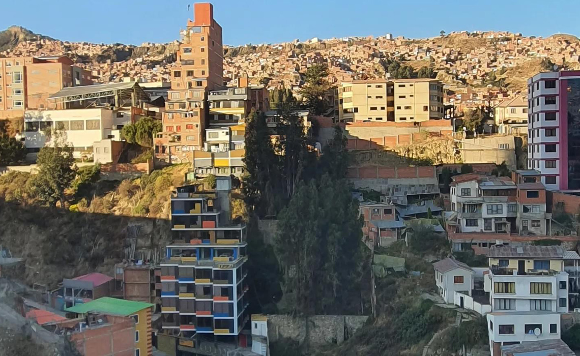 A panoramic view of a mountain range surrounding a vibrant city nestled in the valley below.