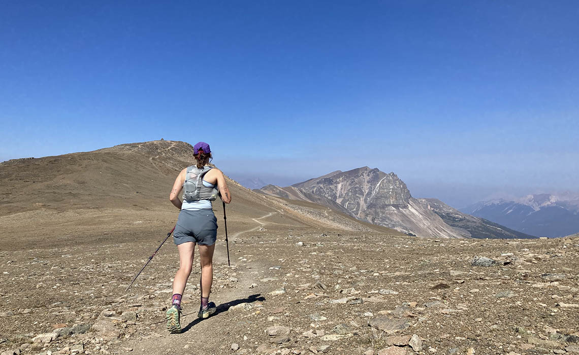 Sierra Hope running on a trail through the mountains.