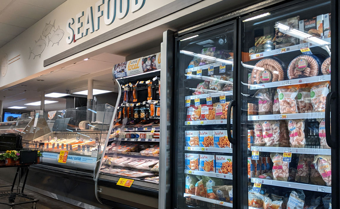 View of the frozen and on-ice fish at the seafood department inside a grocery store.