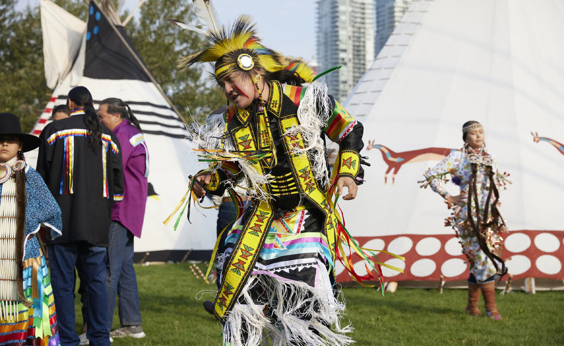 An Indigenous man performs a dance at the Elbow River Camp.
