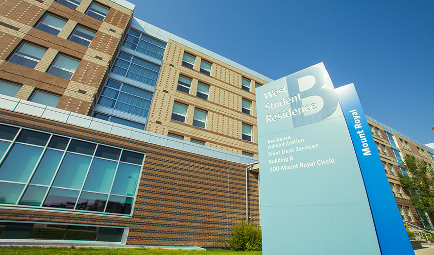 A geometric patterned building with lots of windows and a sign labeling this location as West Student Residence