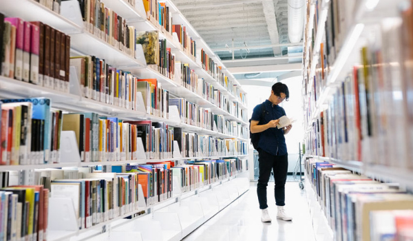 A person looking for a book in the stacks of the Riddell Library and Learning Centre.