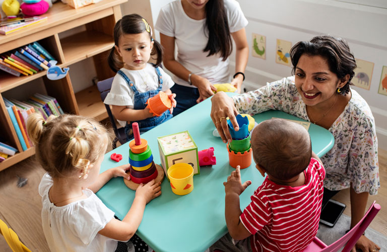Three children playing with table toys with two early childhood educators
