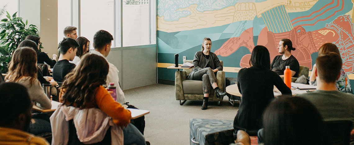 A group of people sitting in a circle in the Slate Innovation Lab having a discussion.