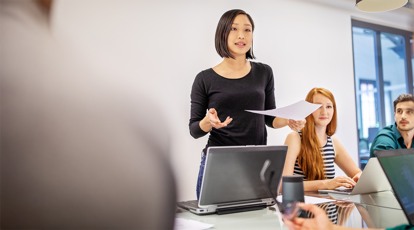 Confident female professional presenting to colleagues in a meeting.