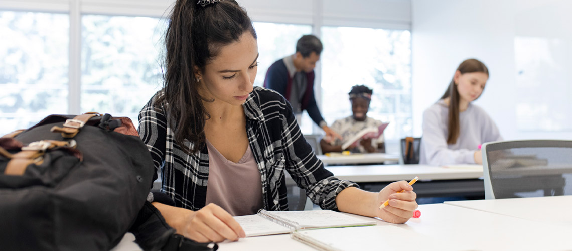 A student diligently writes notes at her desk.