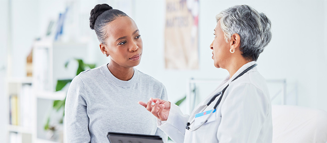 A woman consults with a doctor, discussing her health in a professional medical setting.